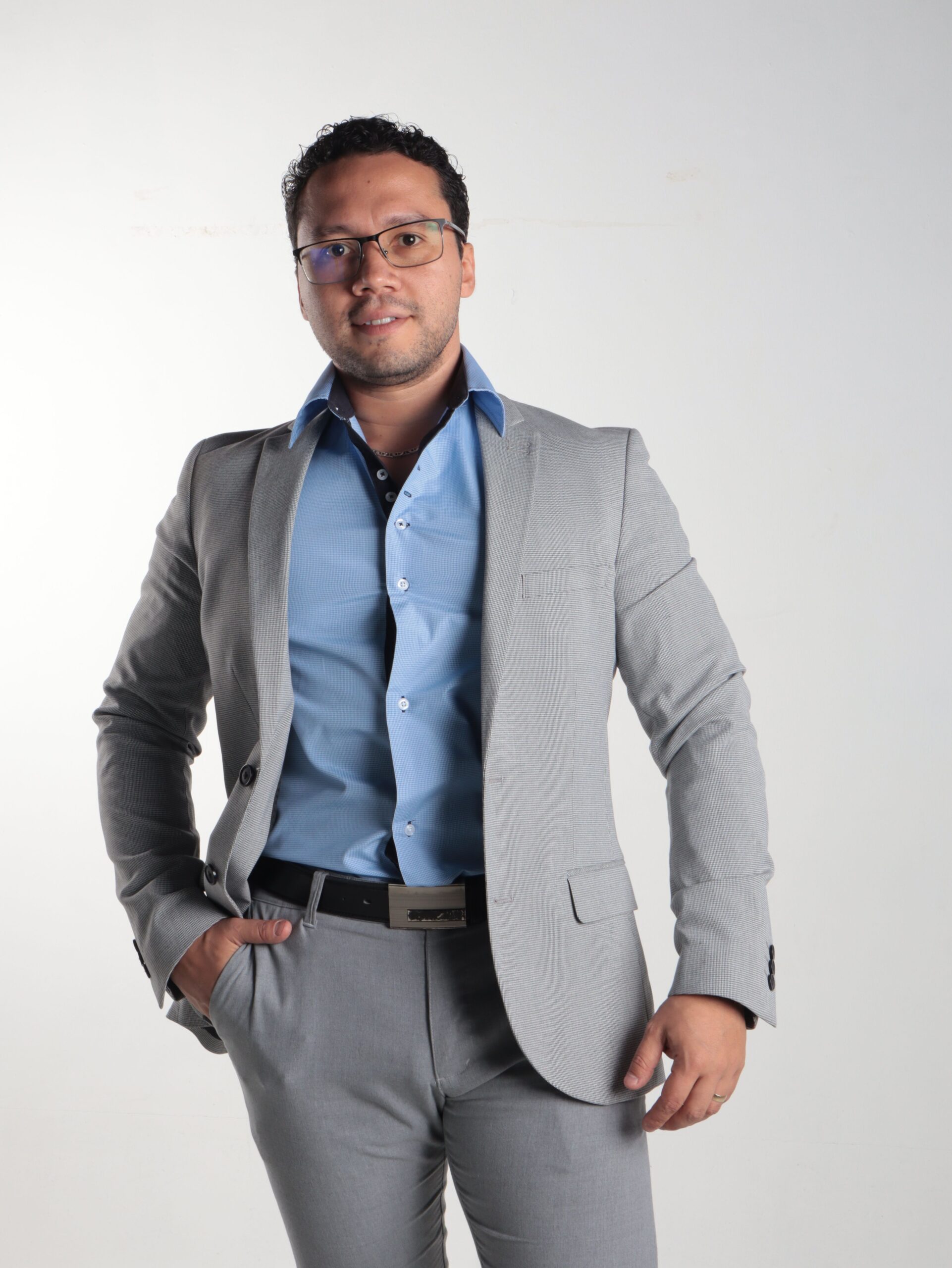 Confident man in grey suit and blue shirt poses for a professional portrait.