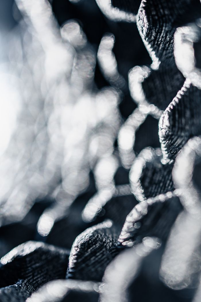 Close-up of abstract metallic structure with intricate textures and patterns, showcasing light play and contrast.